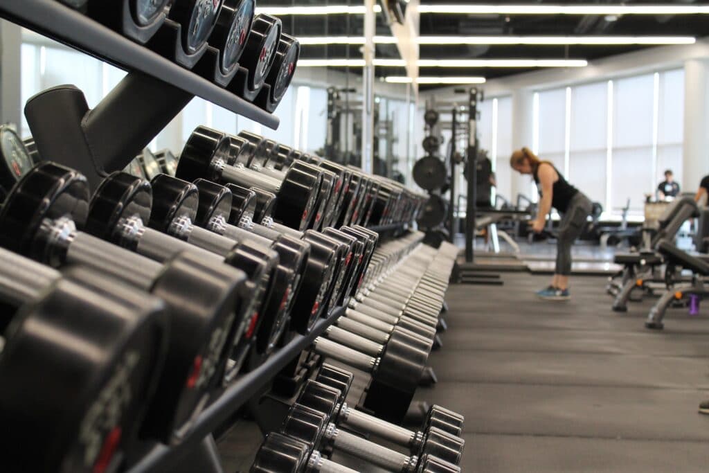 gimnasio con mujer en el fondo haciendo hombros